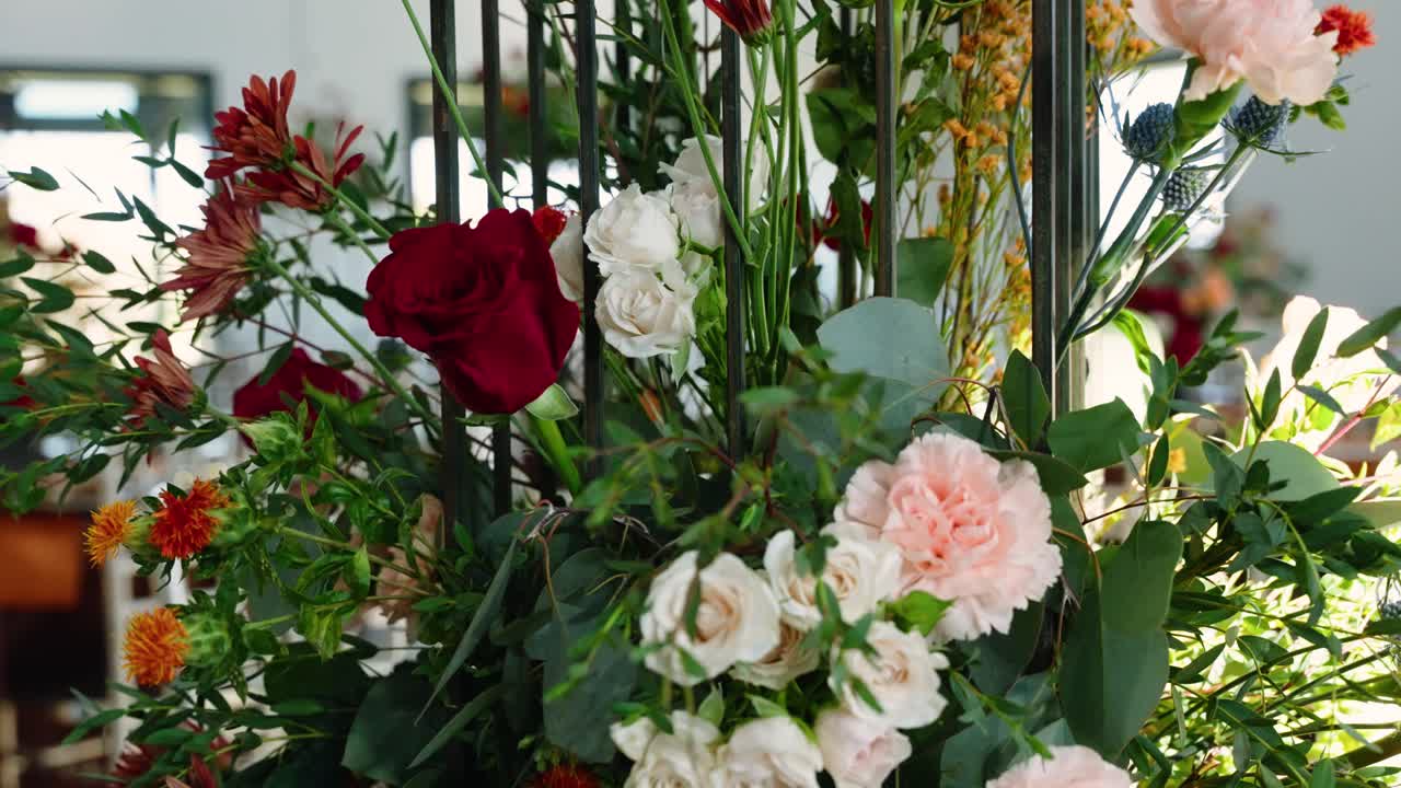 Detailed shot of a lush floral arrangement featuring roses and greenery as table decor at a fall wedding reception.