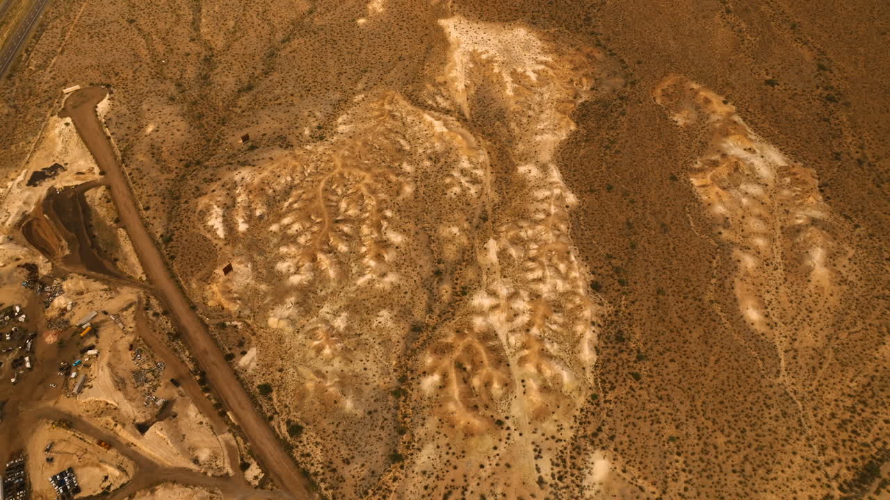 Descending above the driest landscape covered with little plants. Top view over the California desert near the parking lot and highway.