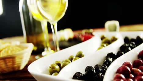 two glasses of wine and a tray with berry fruits and olives