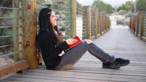 a beautiful black haired girl laughing hysterically in slow motion at the cute red fairytale story book or journal she is reading