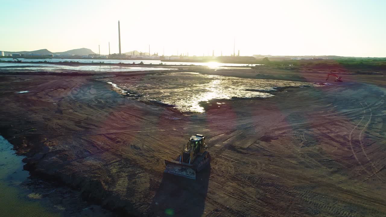 órbita aérea alrededor de la concha tóxica asfalto residuos del lago en curacao al atardecer, estéril no regulado con excavadora