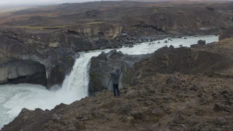 aerial view of photographer taking picture of crashing aldeyjarfoss waterfall in icelandic highlands