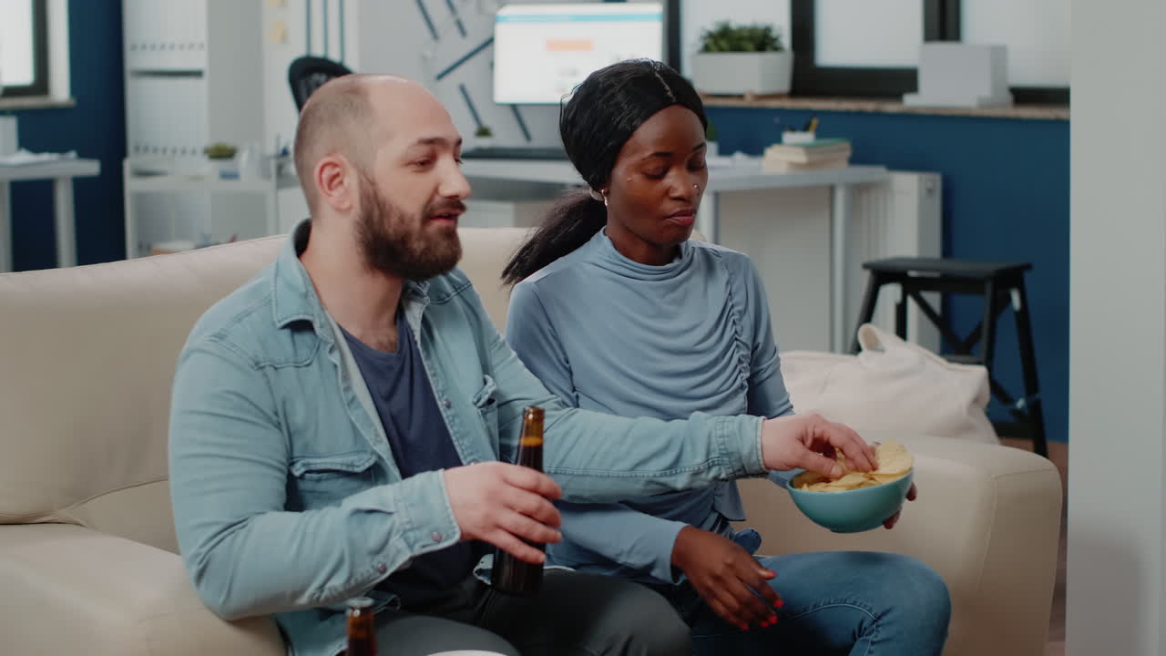 Man and african american woman enjoying chips after work