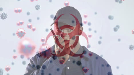 digital composite video of hazard sign with covid-19 cells moving against man using a walkie talkie