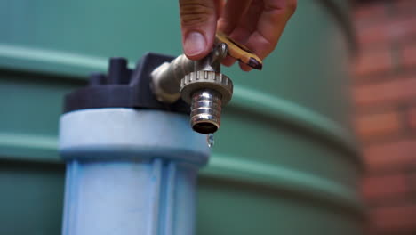 Slow-mo-male-caucasian-hand-fixes-dripping-tap-on-water-tank,-close-up