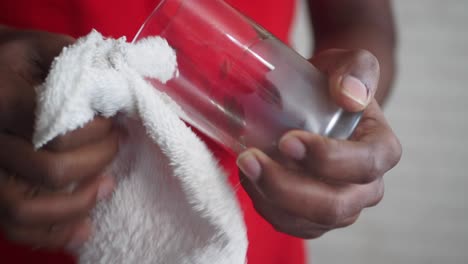 person cleaning a glass with a white cloth