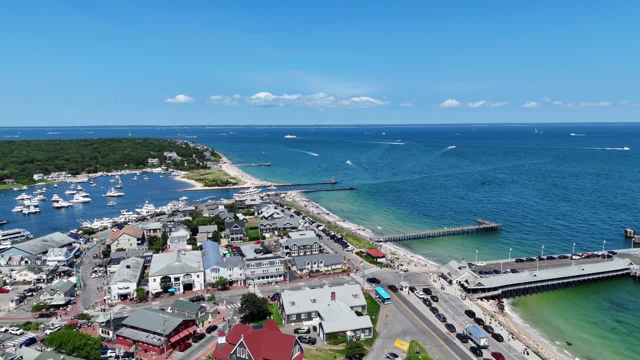 Flygfoto med drönare över Martha’s Vineyard i Dukes County, Massachusetts, som visar kuststad, hamn, pir och turkosa Atlantvatten med båtar och naturskön kustlinje en ljus sommardag. Överflygning.