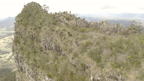 4k toma en órbita de drones de excursionistas caminando al lado de un acantilado de la columna vertebral de la montaña en el parque nacional border ranges, nueva gales del sur, australia