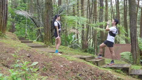 Asian couple taking photos during outdoor adventure in forest