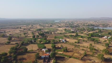 Aerial-drone-shot-of-harvested-wheat-farmlands-during-summer-in-a-rural-village-of-orchha-madhya-pradesh-in-india