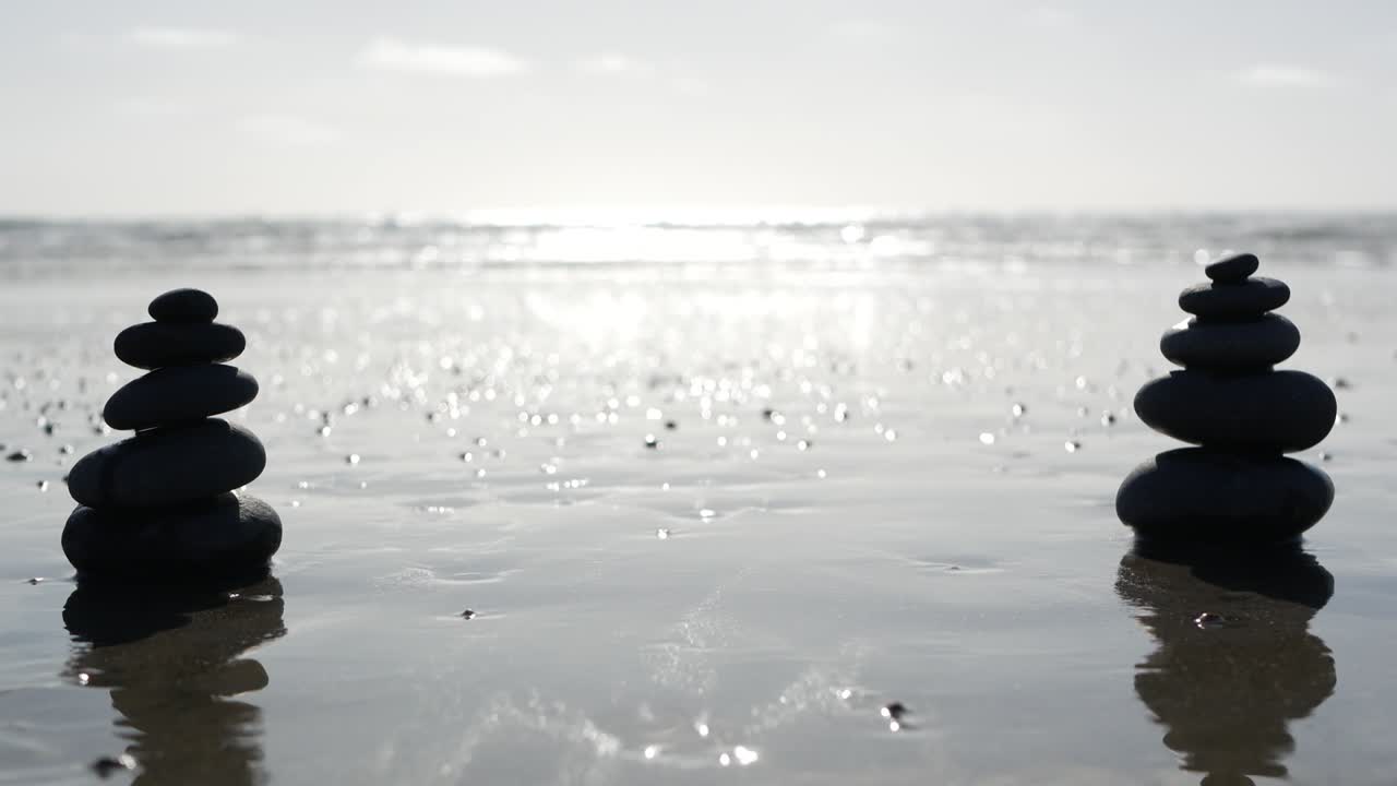 바다 해변에서 바위 균형을 잡고, 바물 파도에 의해 돌이 쌓여, 모래 해변에 있는 자갈의 피라미드.