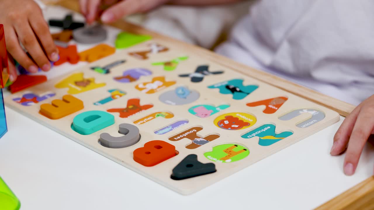 Child arranges colorful wooden alphabet puzzle pieces on table, bright lighting, close-up perspective