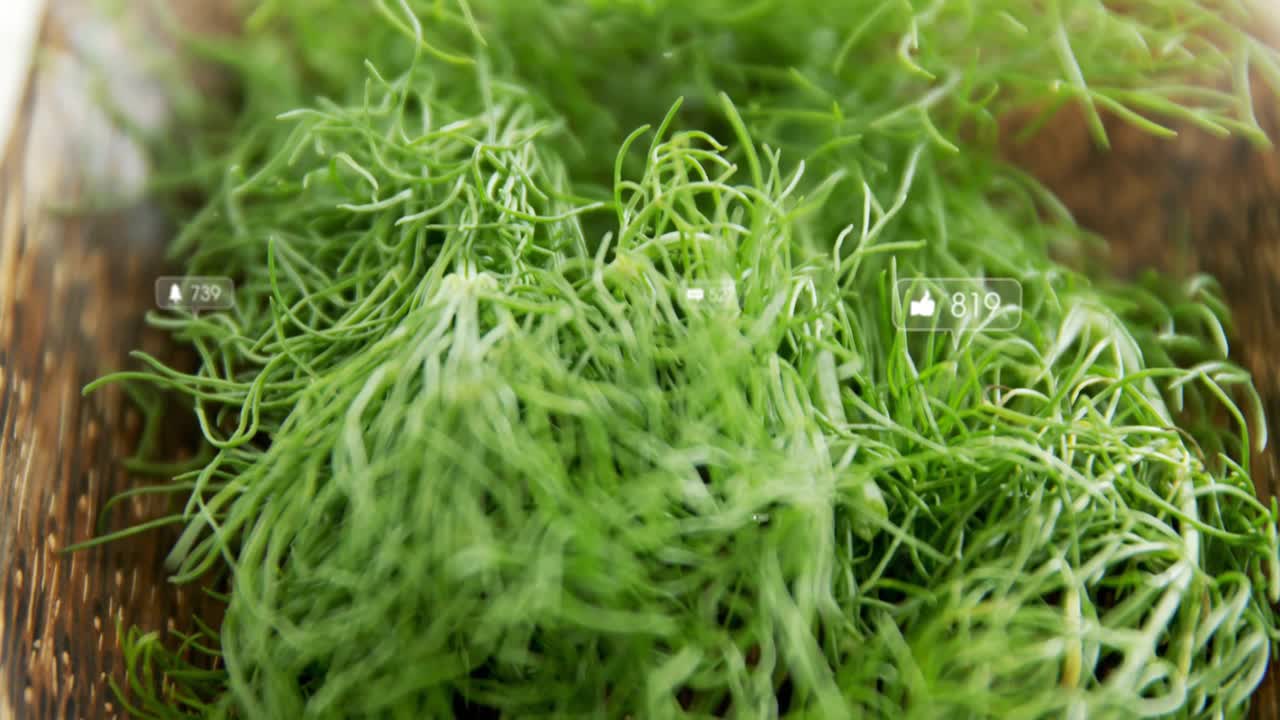 Fios de ervas verde-claras sendo exibidos em uma tábua de corte com ícones de notificação digital flutuantes