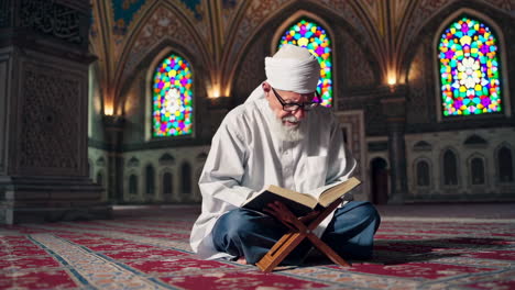 elderly muslim man reading the quran in a mosque