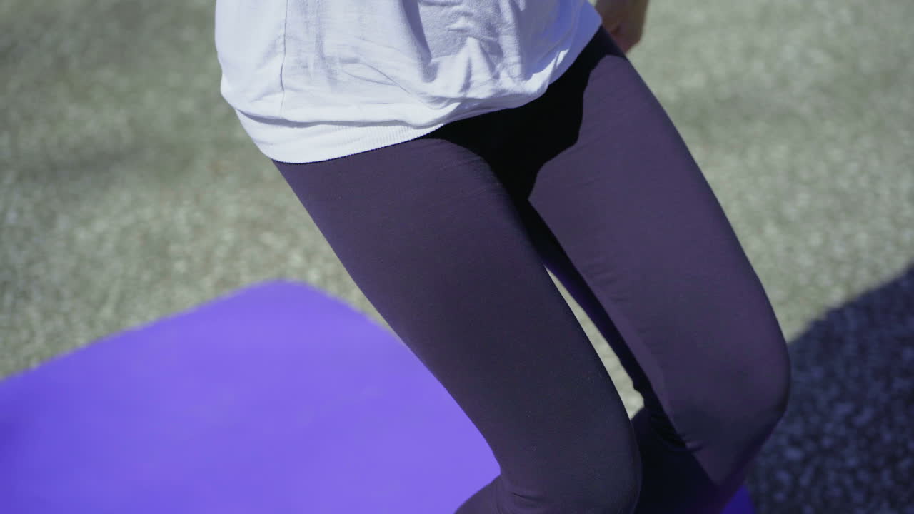 una anciana sonriente sentada en un tapete en el parque.