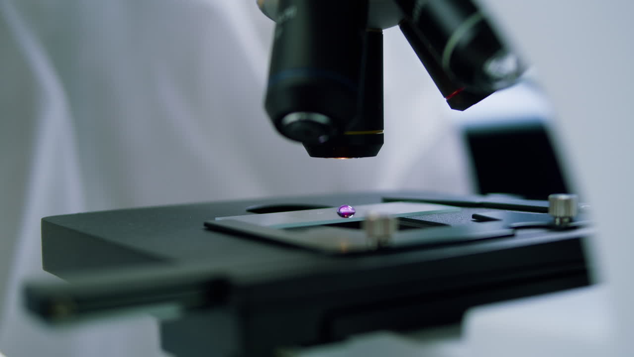 Scientist Placing Sample Slide Under Microscope in Laboratory