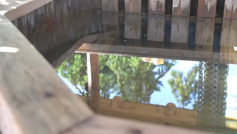 bañera de hidromasaje a leña con aguas tranquilas y ondulantes y árboles que reflejan desde atrás