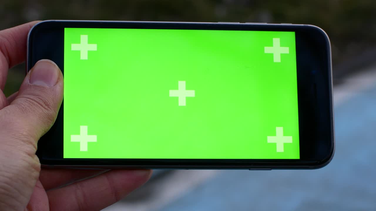 공원 b에 앉아있는 동안 그녀의 손에 녹색 화면으로 전화를 들고 있는 소녀