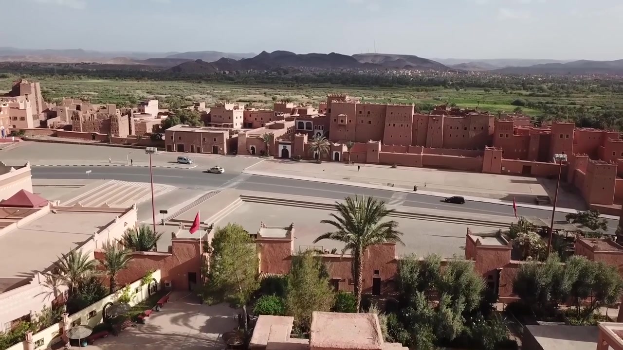 Vista aerea con drone della Kasbah di Taourirt a Ouarzazate, che evidenzia il legame tra il patrimonio storico desertico del Marocco e il vivace paesaggio urbano della porta d'accesso al Sahara.