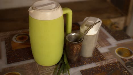 close-up of a pitcher with cold water and ice, along with a guampa and yerba mate with cedar leaves, tereré ready and prepared for consumption, a refreshing traditional paraguayan drink