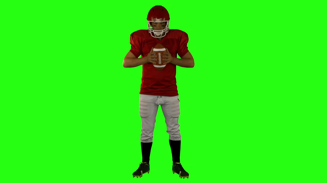 Jogador de futebol americano sério de vermelho posando