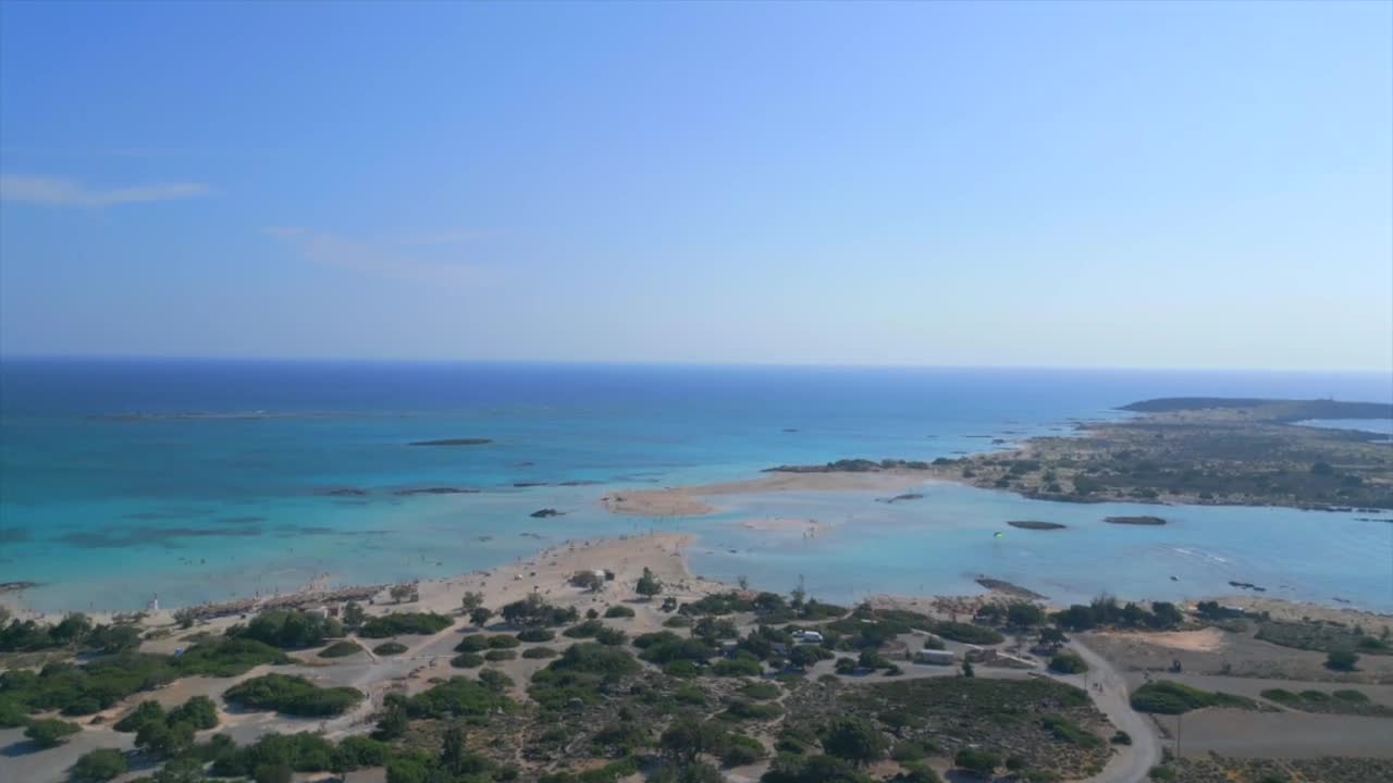 Capture Elafonisi Beach in Crete with drone footage. The shot begins with showing of the island's lush vegetation and gradually ascends to reveal the shallow waters connecting Crete to Elafonisi