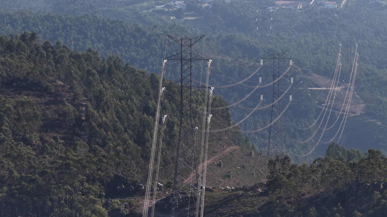 Energy power lines and high voltage towers across the Eucalyptus monocultures in Portugal drone zoom shot