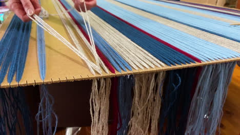 woman attaching colorful threads of wool for weaving