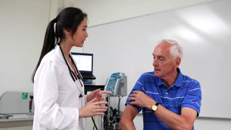 el médico hablando con un paciente con dolor en el hombro.