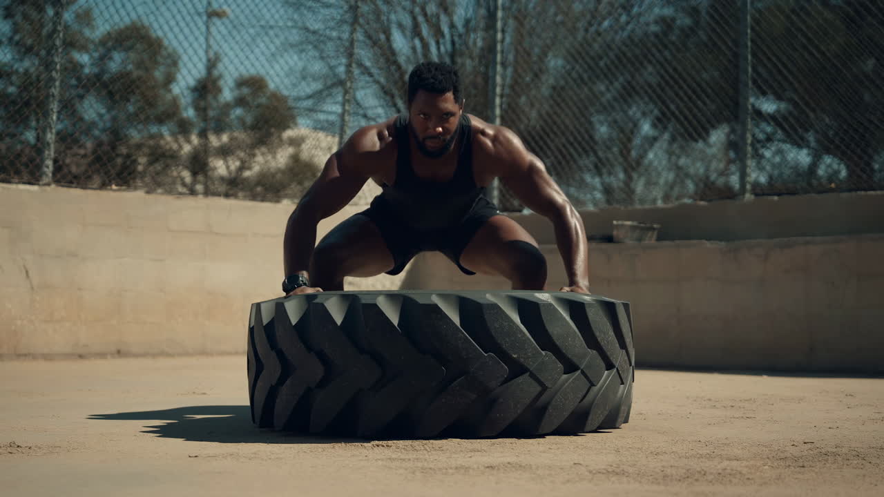 Muskulöser Mann wirft während des Outdoor-Workouts einen schweren Reifen um