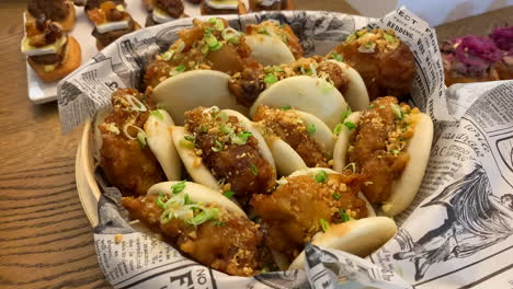 breaded chicken baos with chopped chives on an appetizer table