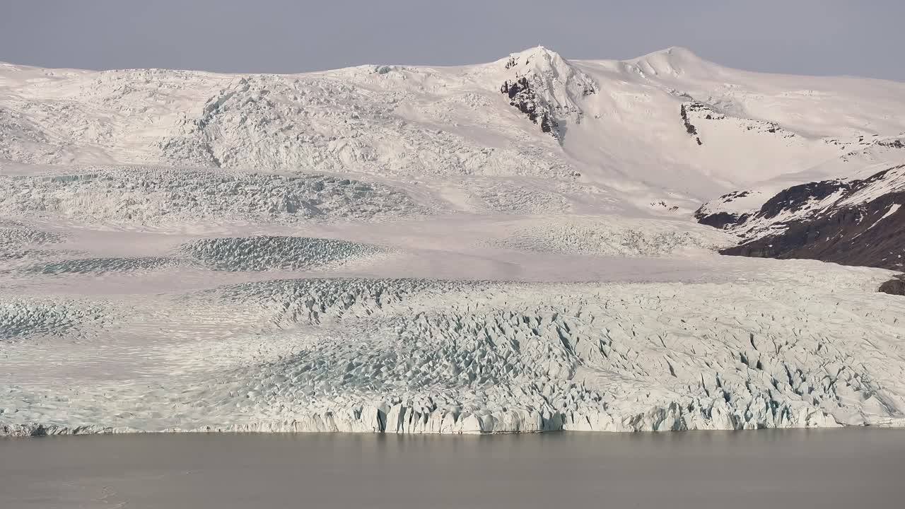 Vatnajökull National Park in Iceland - aerial view of Fjallsárlón glacier tongue, with snow-covered land and an icy lake shore.