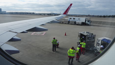 The-hustle-and-bustle-of-the-runway:-A-window-view-of-airport-ground-crews-at-work