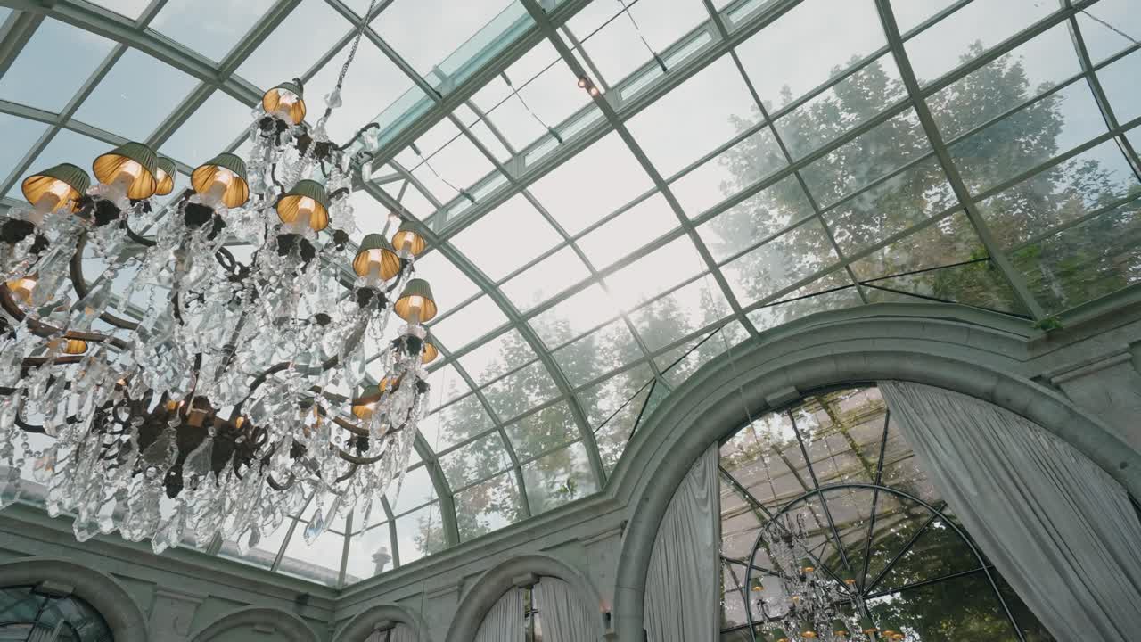 lampadario decorato sospeso sotto un tetto di vetro ad arco in un raffinato interno classico
