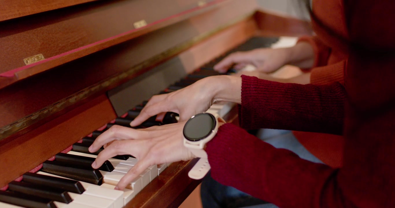 Jari-jari mendarat di tuts memulai dua pasang tangan bermain duet di piano tegak