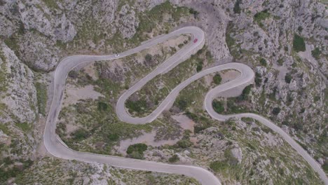 top down shot of car driving at mountain pass coll dels reis mallorca during day time, aerial