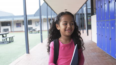 in a school courtyard, a young hispanic girl smiles brightly