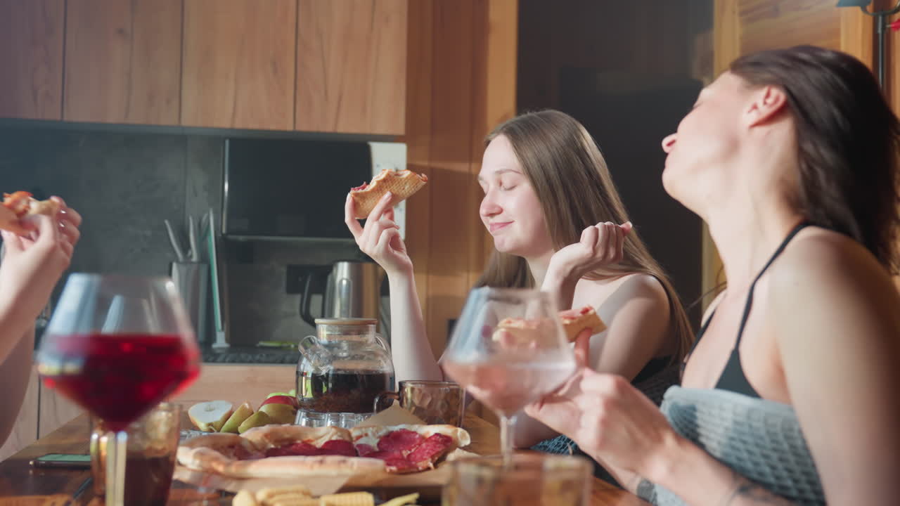 Youngsters enjoying themselves eating pizza together, sharing laughter and good vibes in a cozy indoor setting, captured in a lively moment, savoring pizza with friends and relaxing