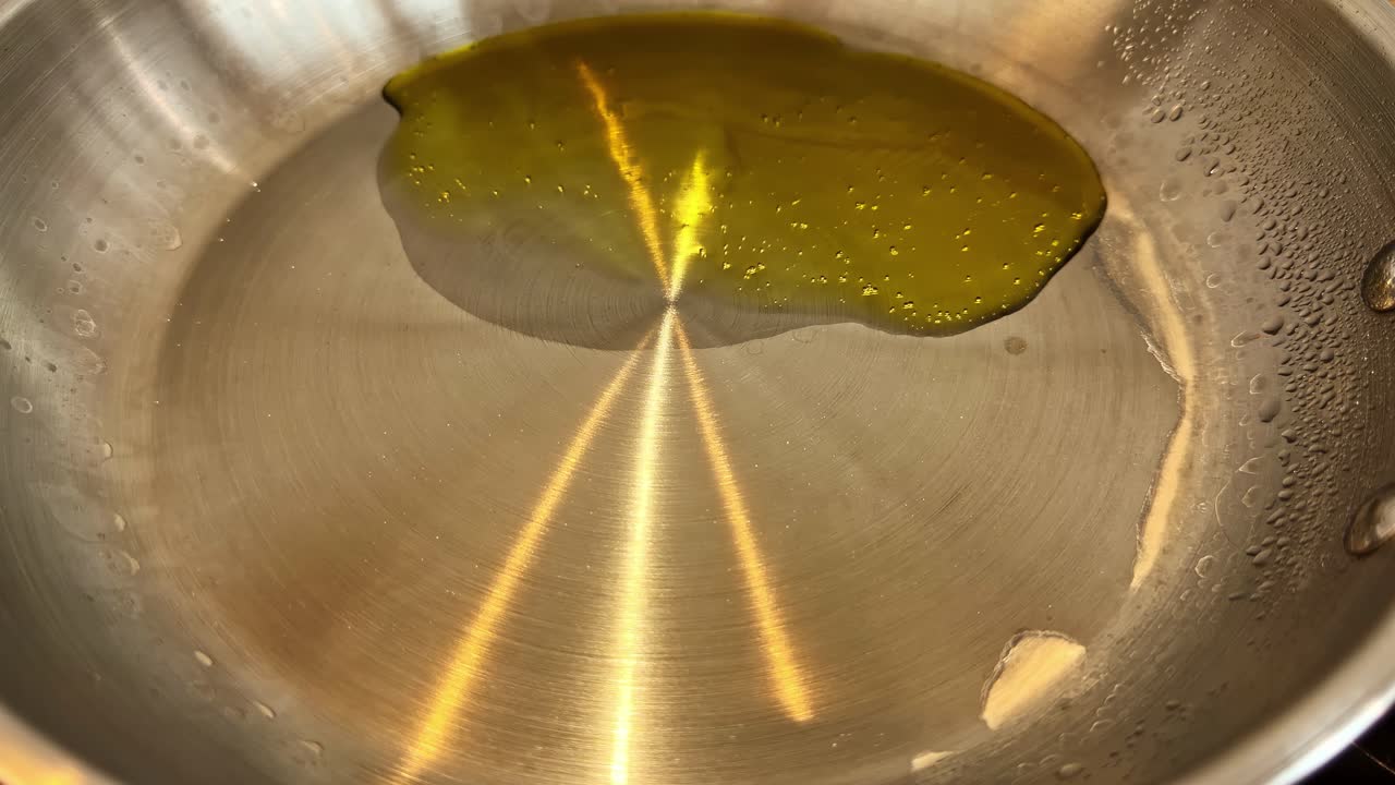 Verdure verdi tagliate a pezzetti sfrigolano in una padella calda, luccicando nell'olio mentre si ammorbidiscono, creando una vista ravvicinata di prodotti freschi che cuociono con una consistenza ricca e colori naturali