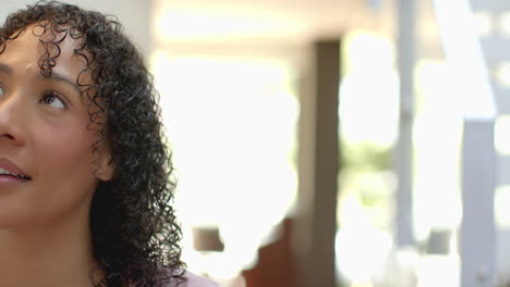 smiling woman with curly hair looking away, enjoying peaceful moment at home, copy space