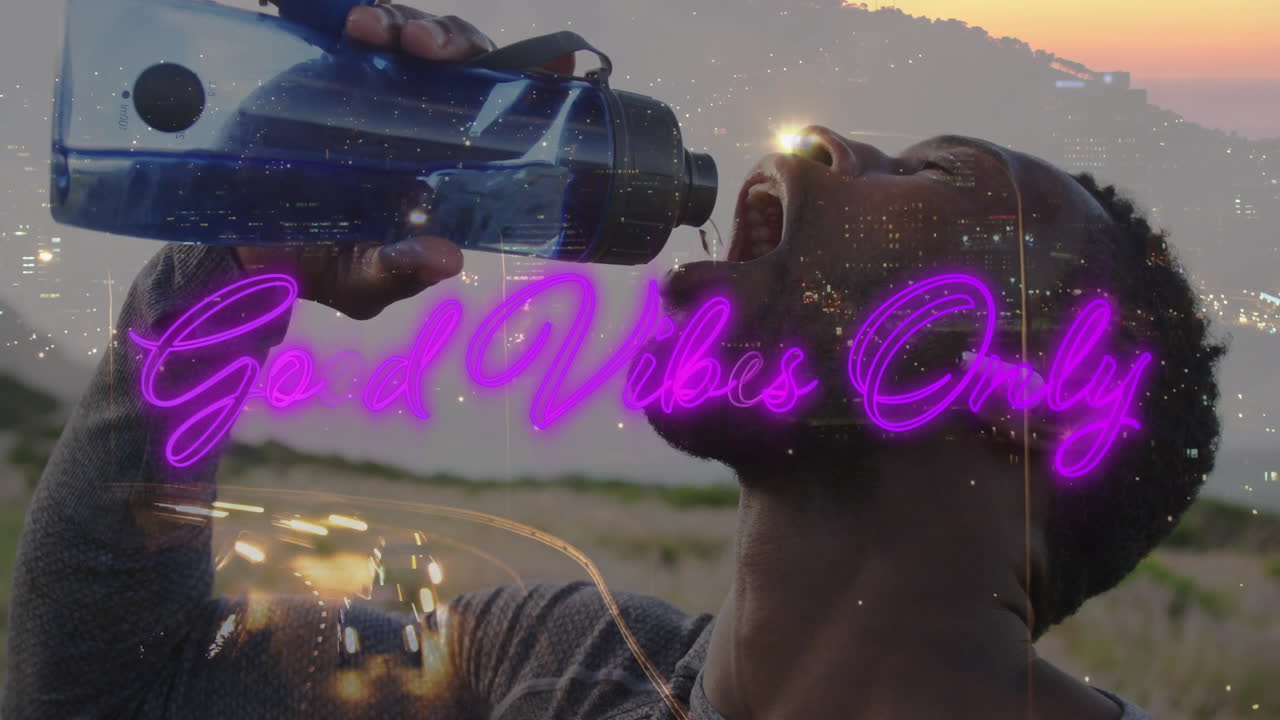 Man drinking water outdoors at dusk, showcasing fitness theme with neon text and light trails