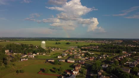flying over a suburban neighborhood, toward a beautiful half rainbow