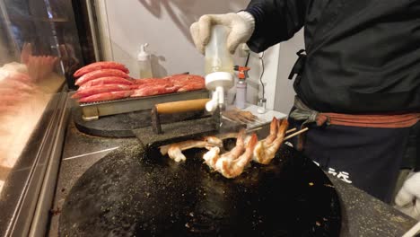 chef grills shrimp skewers on an outdoor griddle