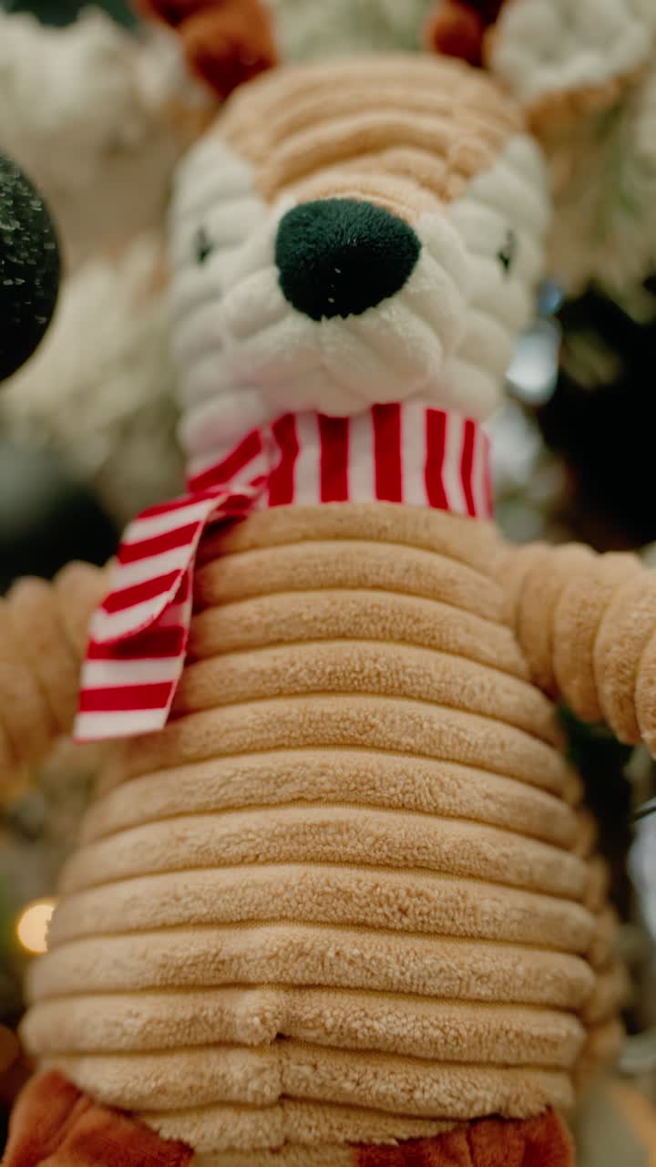 Close Up of Cute Stuffed Reindeer Toy with Red Scarf on Christmas Tree