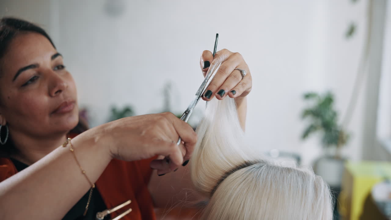 Kadeřnice stříhá blond vlasy nůžkami v kadeřnickém salonu