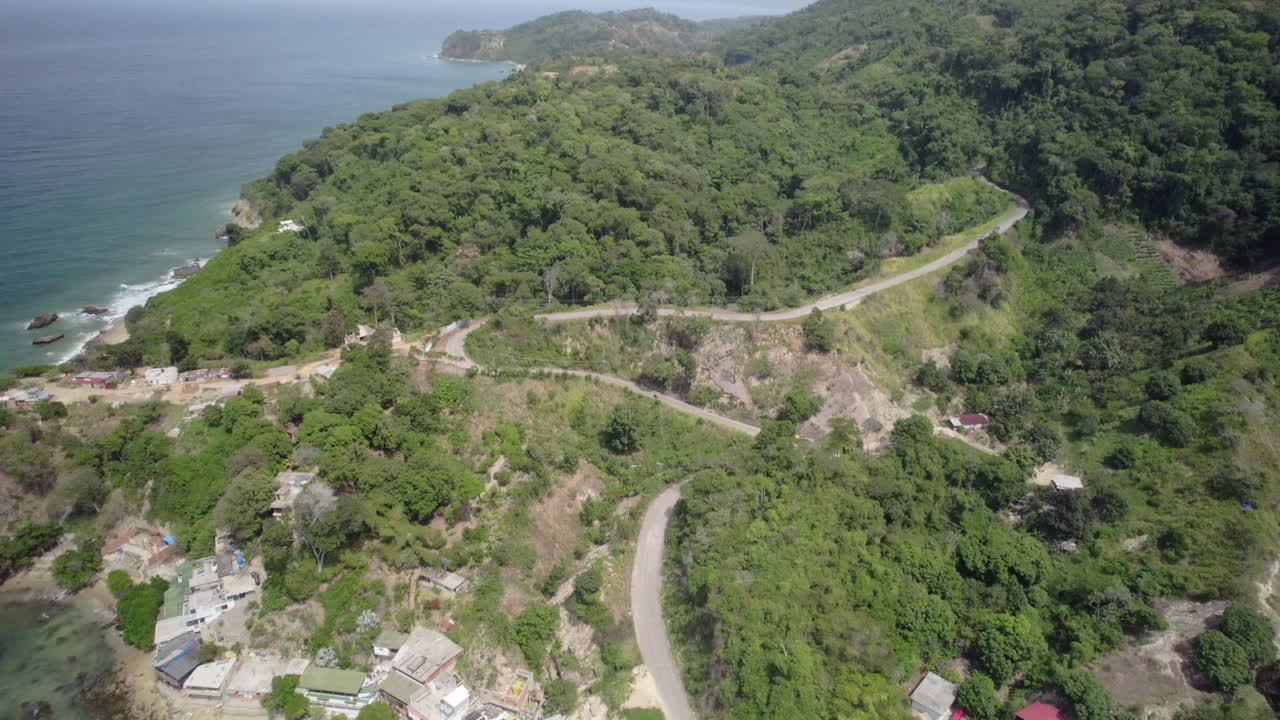 Green coastal mountains and a winding road leading to a scenic beach view