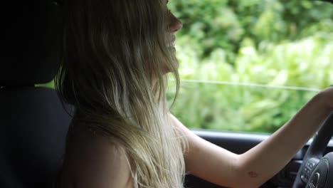 slow motion attractive woman driving and smiling with the window down