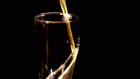 pouring cold wheat beer into a spinning weizen glass isolated in black background