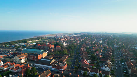 Watch-aerial-footage-of-Skegness,-Lincolnshire,-highlighting-its-stunning-coastline,-busy-tourist-town,-and-famous-pier-on-a-summer-evening