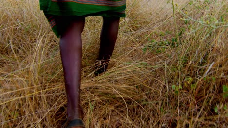 feet of indigenous karamojong warrior hunting through high grass in uganda, africa. tracking shot